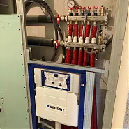 Az Ösküben található HydroArt Kft. épületgépészeti munkálatainak részeként látható a képen egy modern fűtéstechnikai berendezés. Az eszközön több cső és szeleprendszer található, amelyek a hőmérséklet szabályozását segítik elő. Az esztétikus kivitelezés és a precíz csatlakozások biztosítják a hatékony működést az épületgépészet területén.